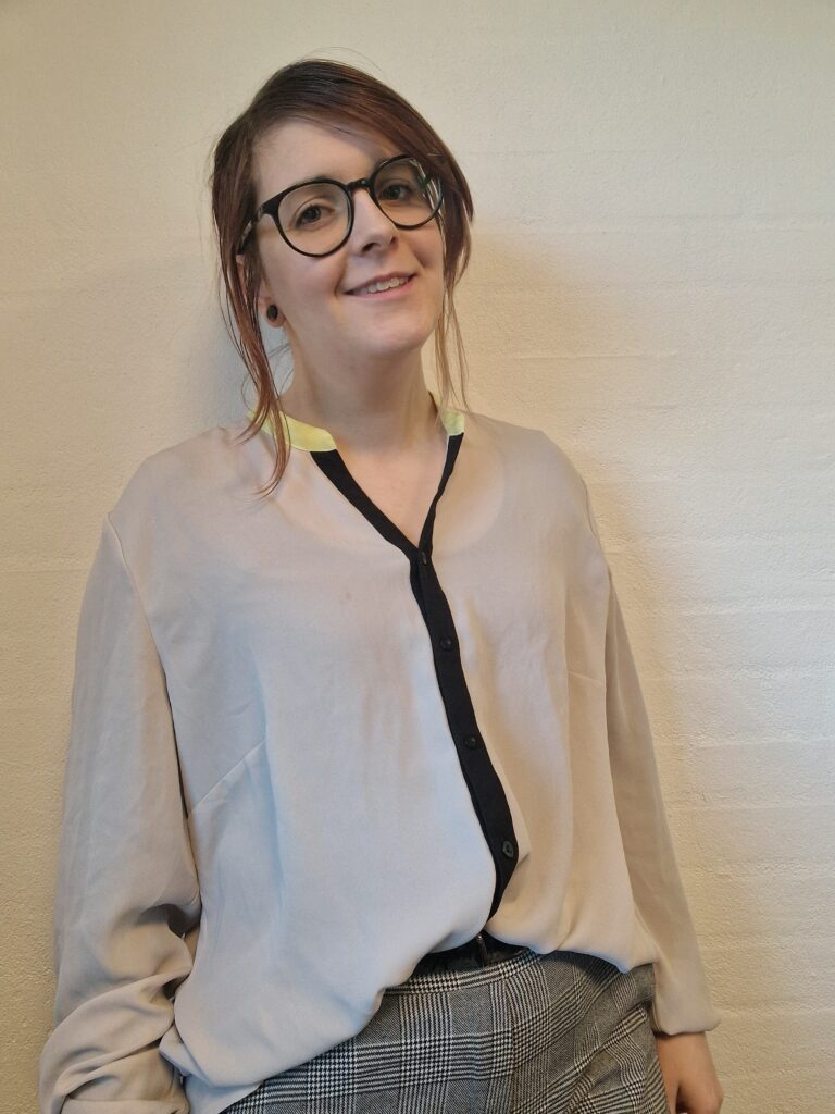 Kvinde i professionelt tøj, smiler til kamera foran hvid baggrund